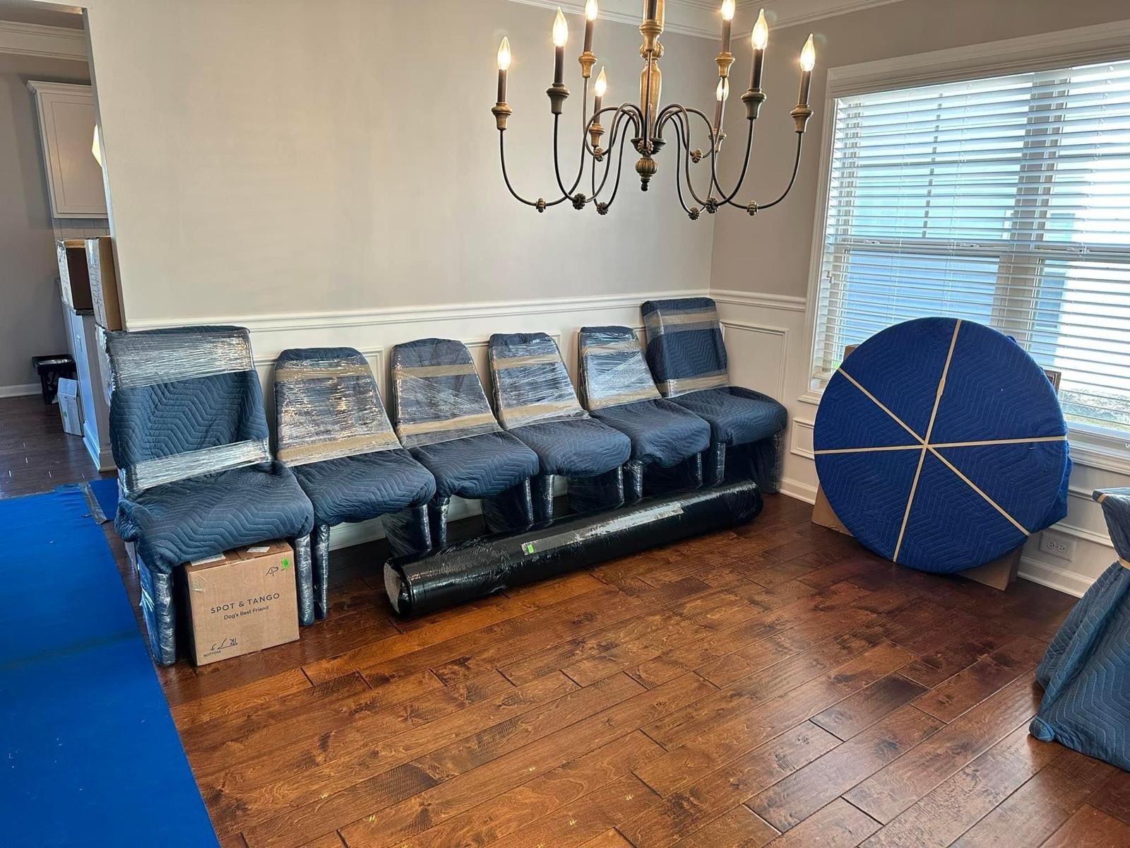 Dining chairs and a round table top padded and wrapped for moving